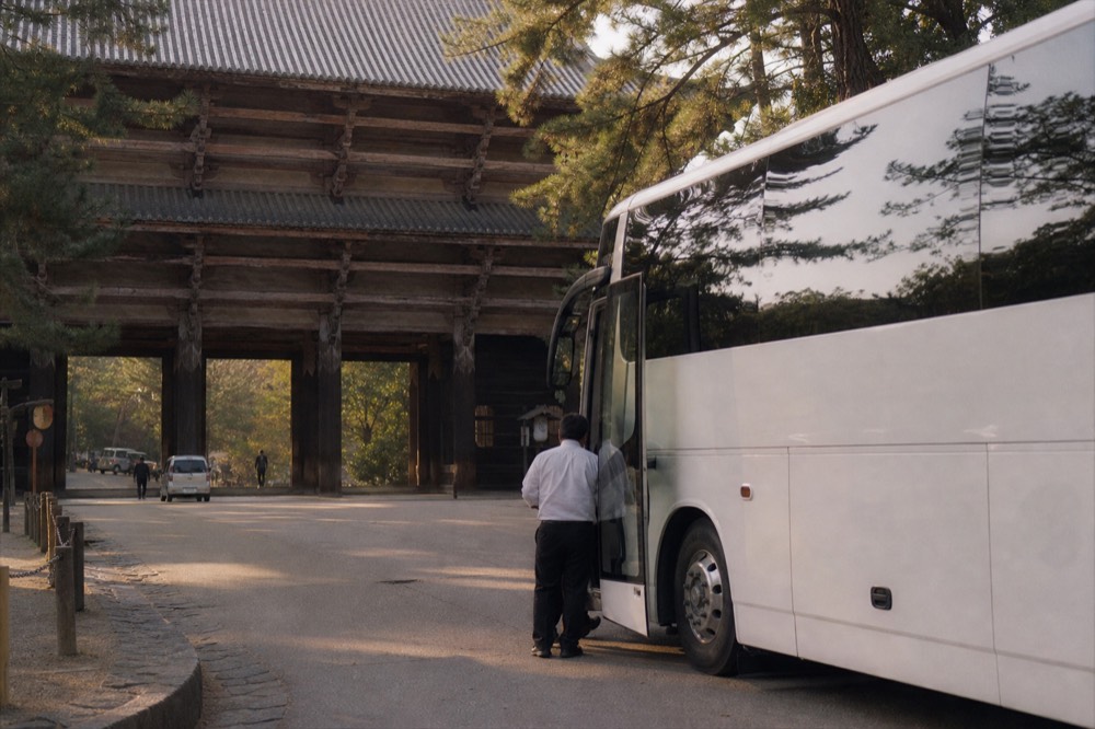Coach parked on a road beside the gates and trees near Todai-ji in Nara