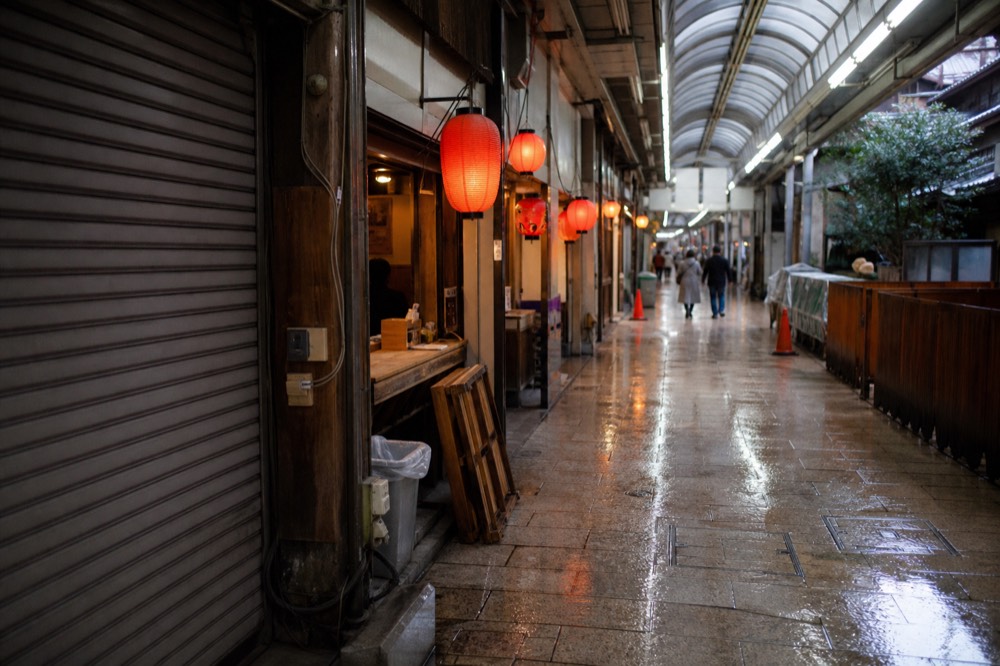 A covered shopping arcade with small food shopfronts and hanging lanterns
