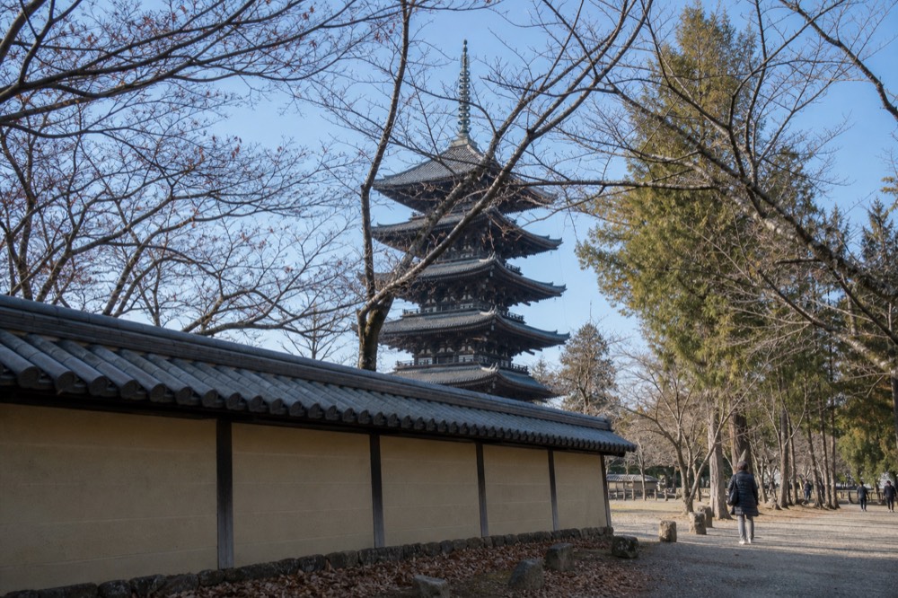 A five-storied wooden pagoda seen through bare winter branches under a clear sky