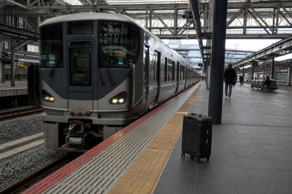 A JR train arriving at Kyoto Station platform with the station's modern glass canopy overhead