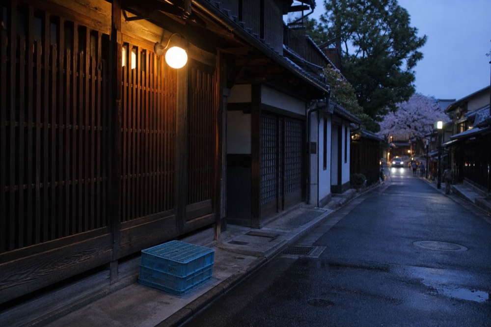 A quiet street of traditional wooden shopfronts in the early evening