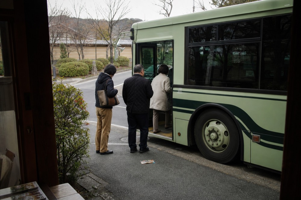 City bus stopped at a kerb with passengers boarding in a narrow street