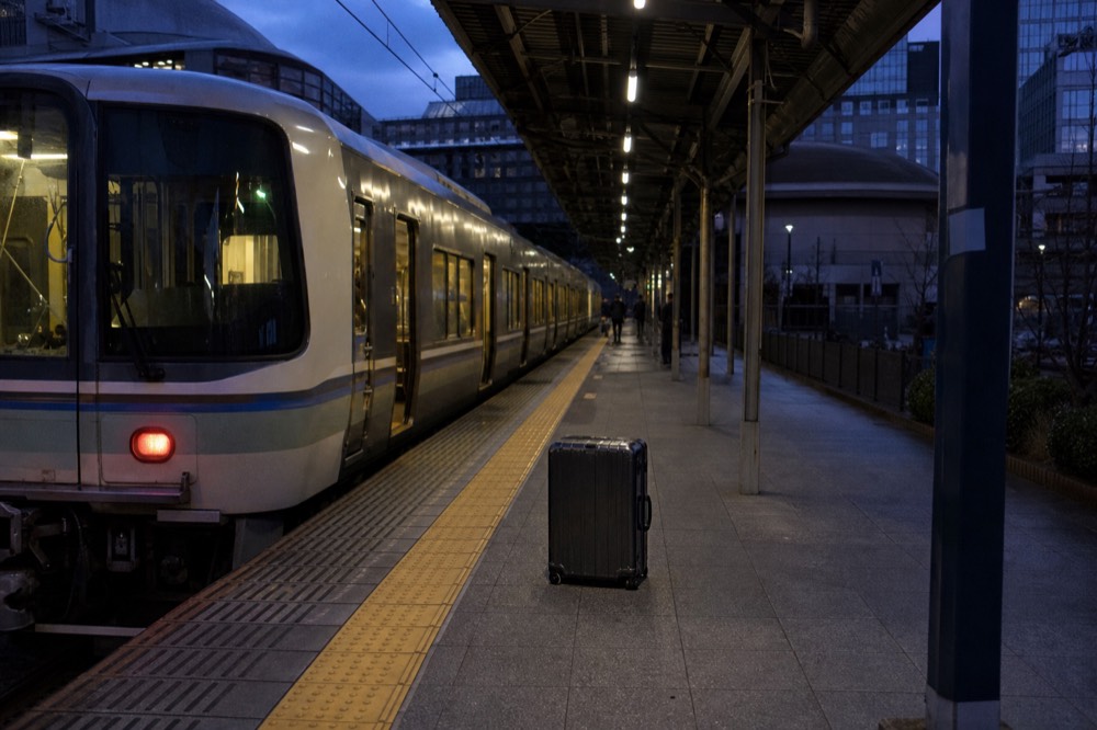 A regional train platform at Kyoto Station with a waiting train at dusk