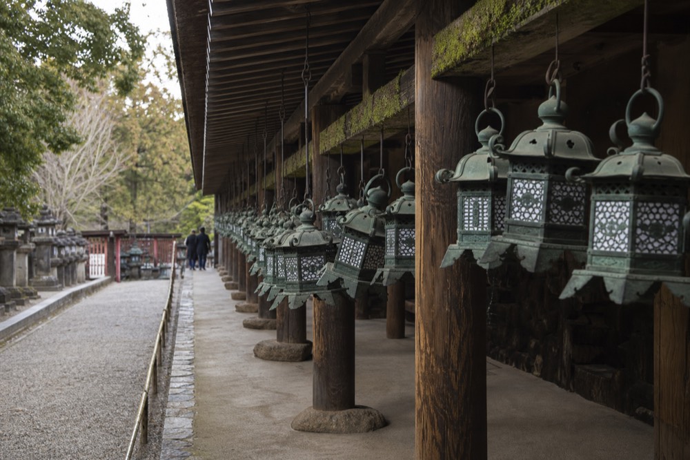 Bronze lanterns hanging along the veranda of a wooden shrine building